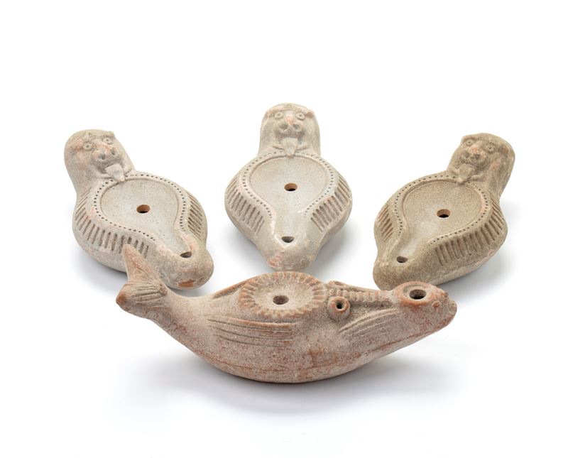 Lotto di quattro lucerne in terracotta con decoro a rilievo imitante pesce e mostro marino