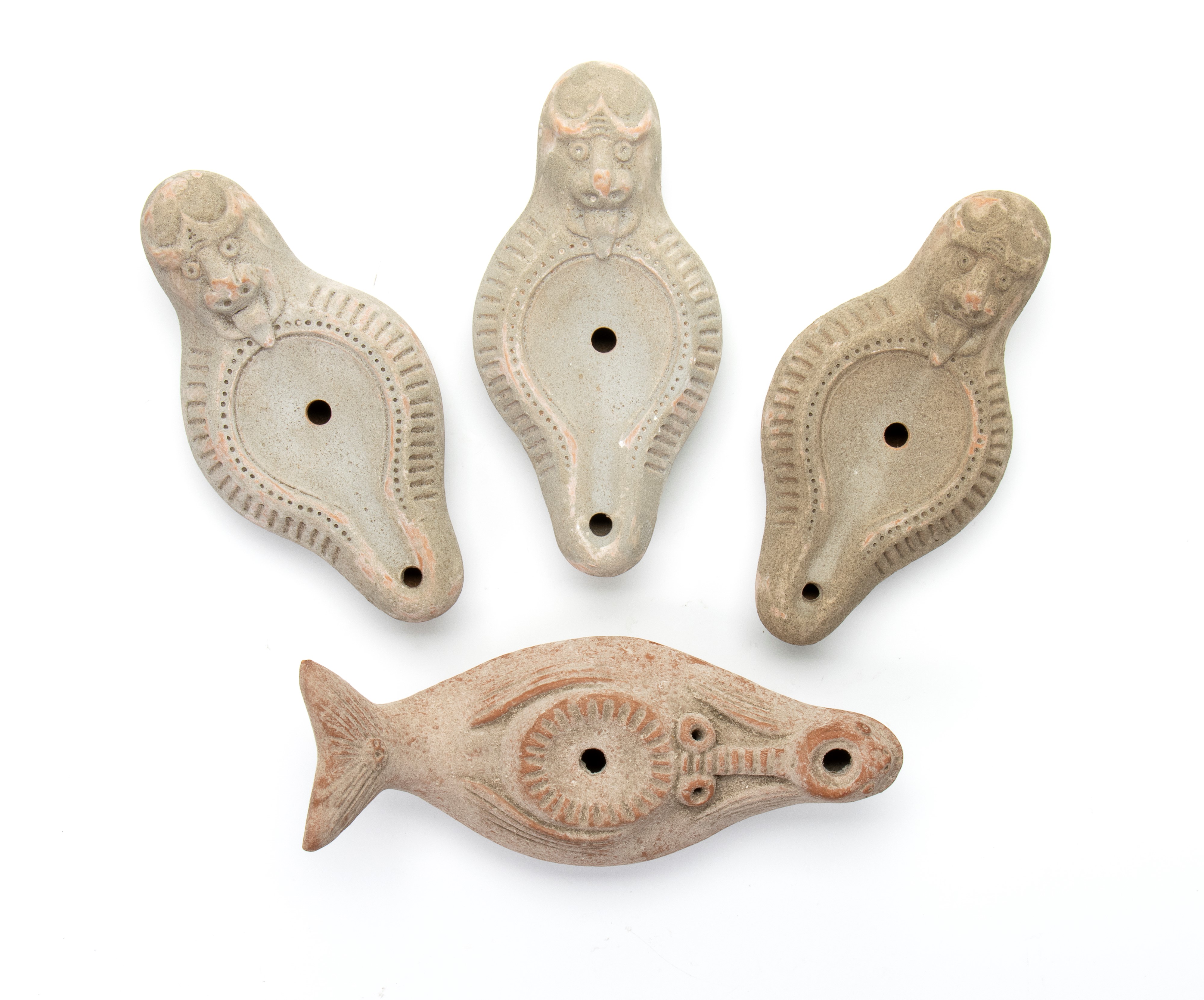 Lotto di quattro lucerne in terracotta con decoro a rilievo imitante pesce e mostro marino