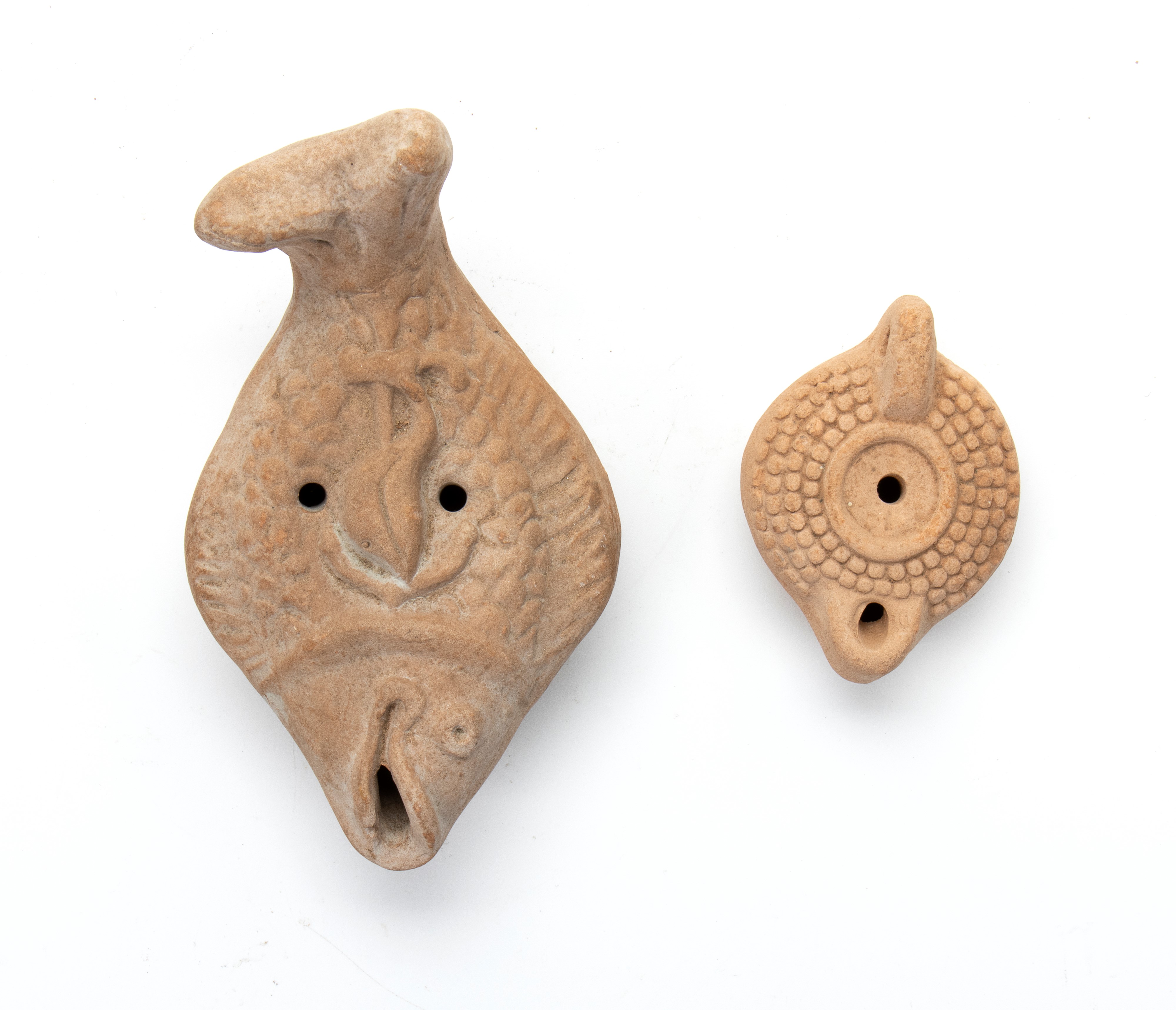 Lotto di due lucerne in terracotta, una a forma di pesce con ancora e defino a rilievo, l'altra c...