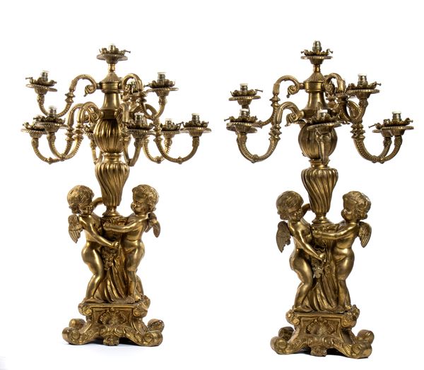 Coppia di candelieri a 9 luci in bronzo dorato e finemente cesellato con putti stanti a trattenere il fusto