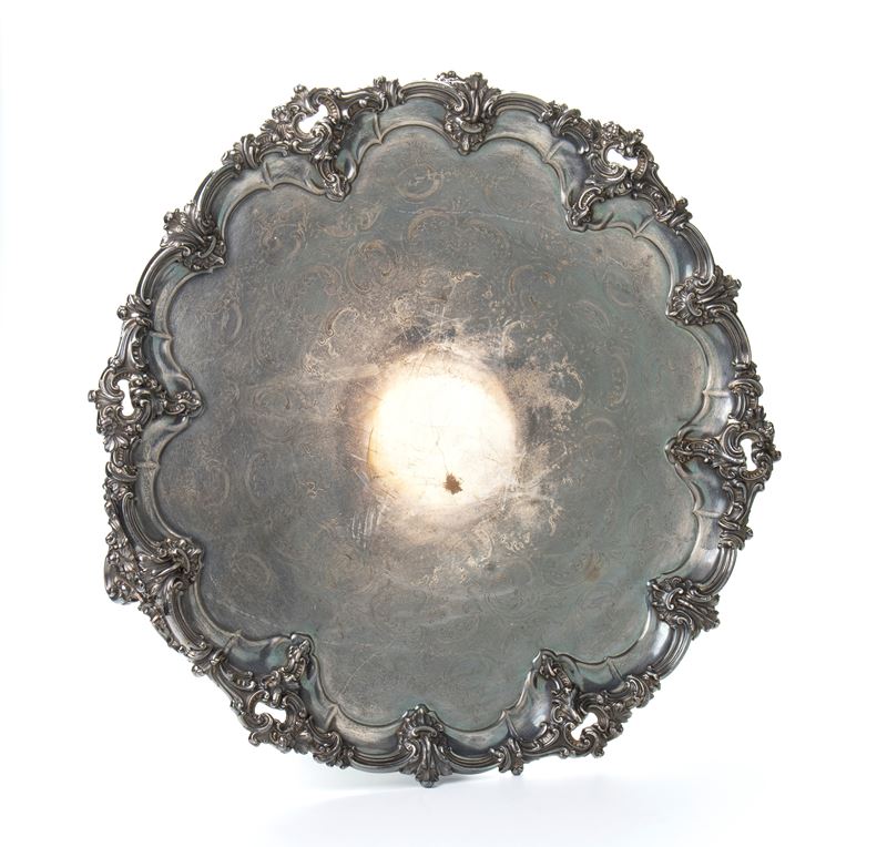 Grande vassoio rotondo in metallo argentato con bordi mistilinei e decoro fitomorfo a rilievo sul...