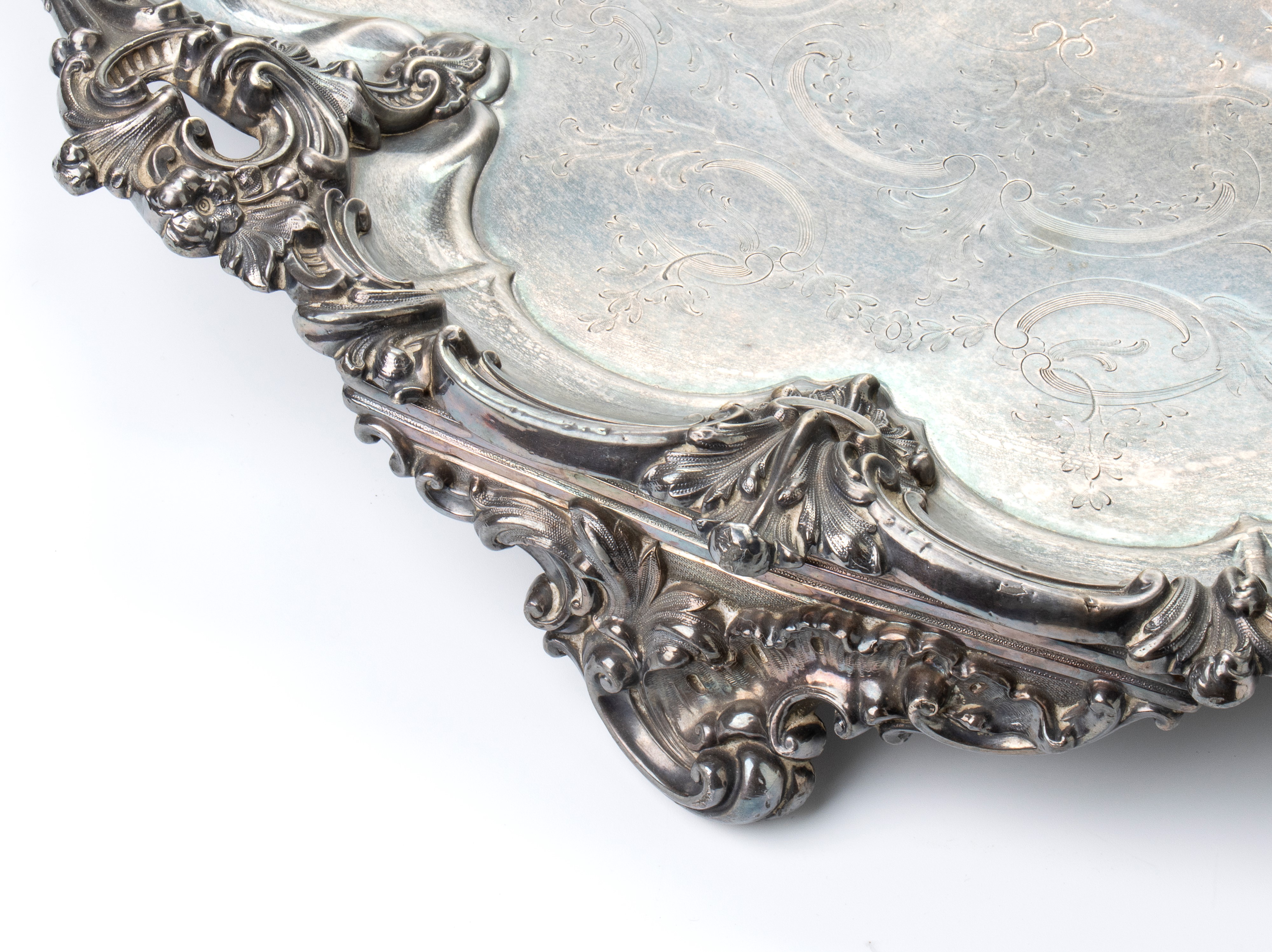 Grande vassoio rotondo in metallo argentato con bordi mistilinei e decoro fitomorfo a rilievo sul...