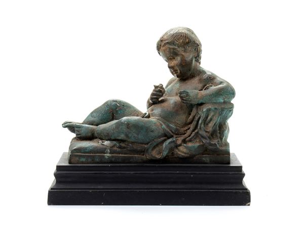 Scultura di putto sdraiato in bronzo su base di legno