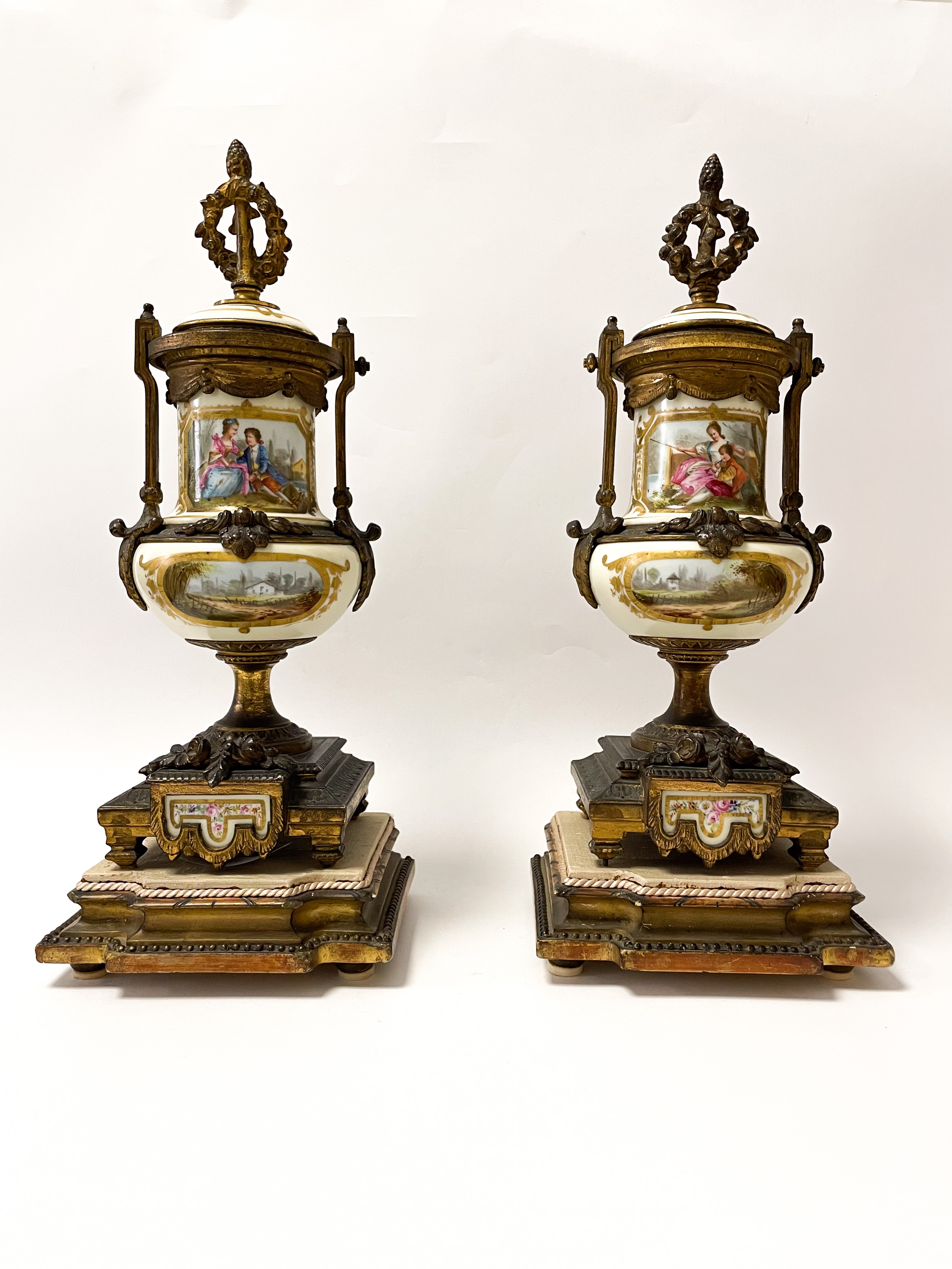 Set di due vasi in bronzo dorato finemente cesellato con inserti floreali. Corona d'alloro e pign...