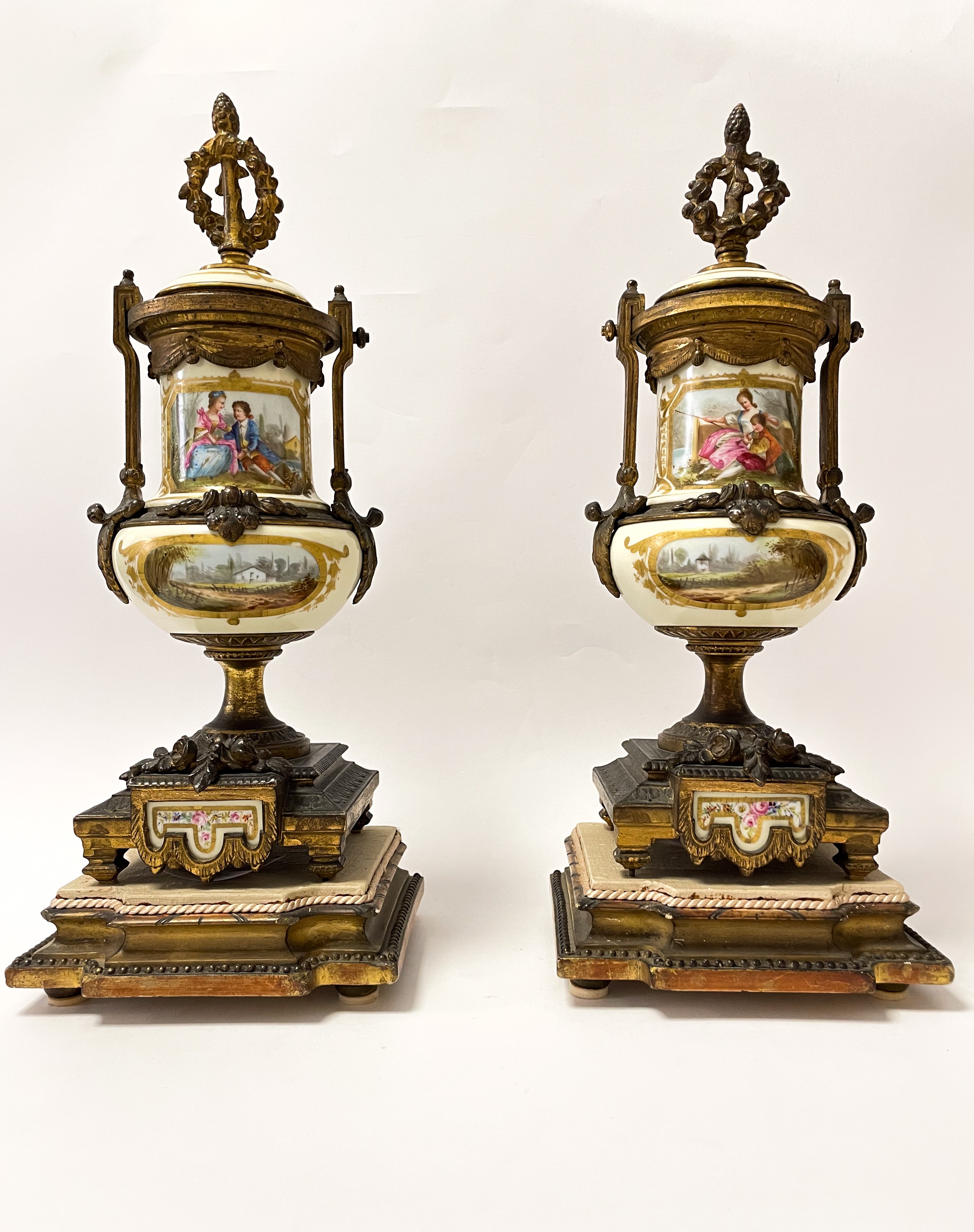 Set di due vasi in bronzo dorato finemente cesellato con inserti floreali. Corona d'alloro e pign...