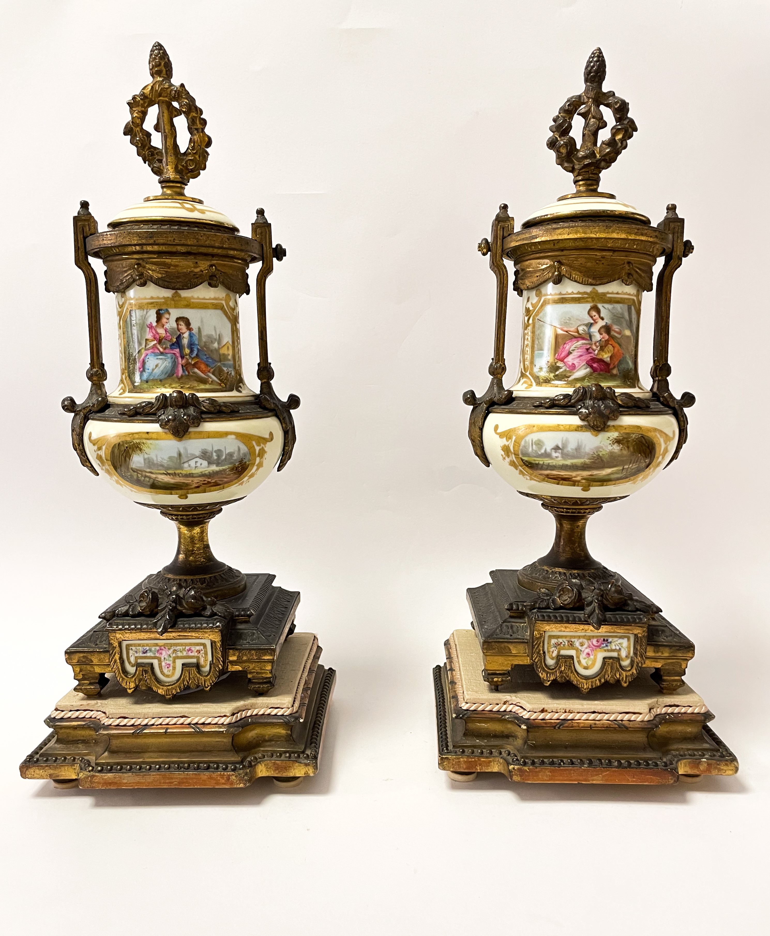 Set di due vasi in bronzo dorato finemente cesellato con inserti floreali. Corona d'alloro e pign...