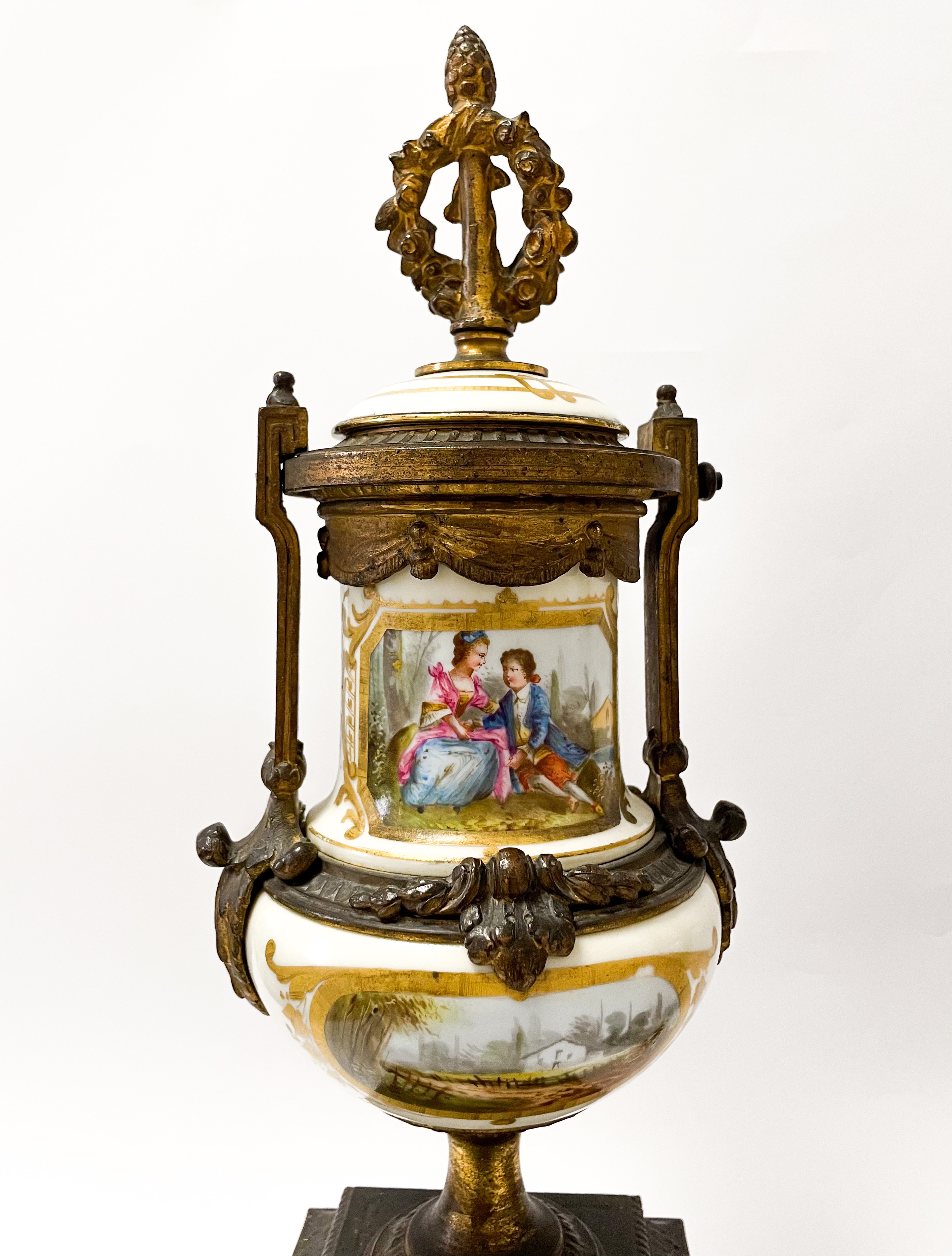 Set di due vasi in bronzo dorato finemente cesellato con inserti floreali. Corona d'alloro e pign...