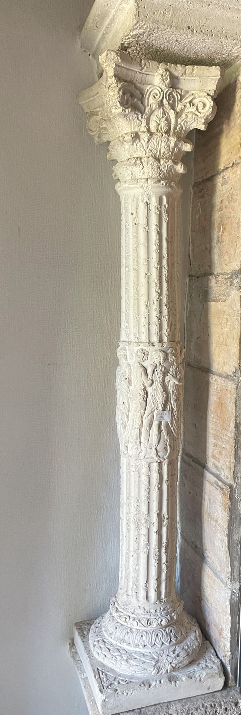 Coppia di sottili colonne corinzie in polvere di marmo e cemento con teoria di togati al fusto