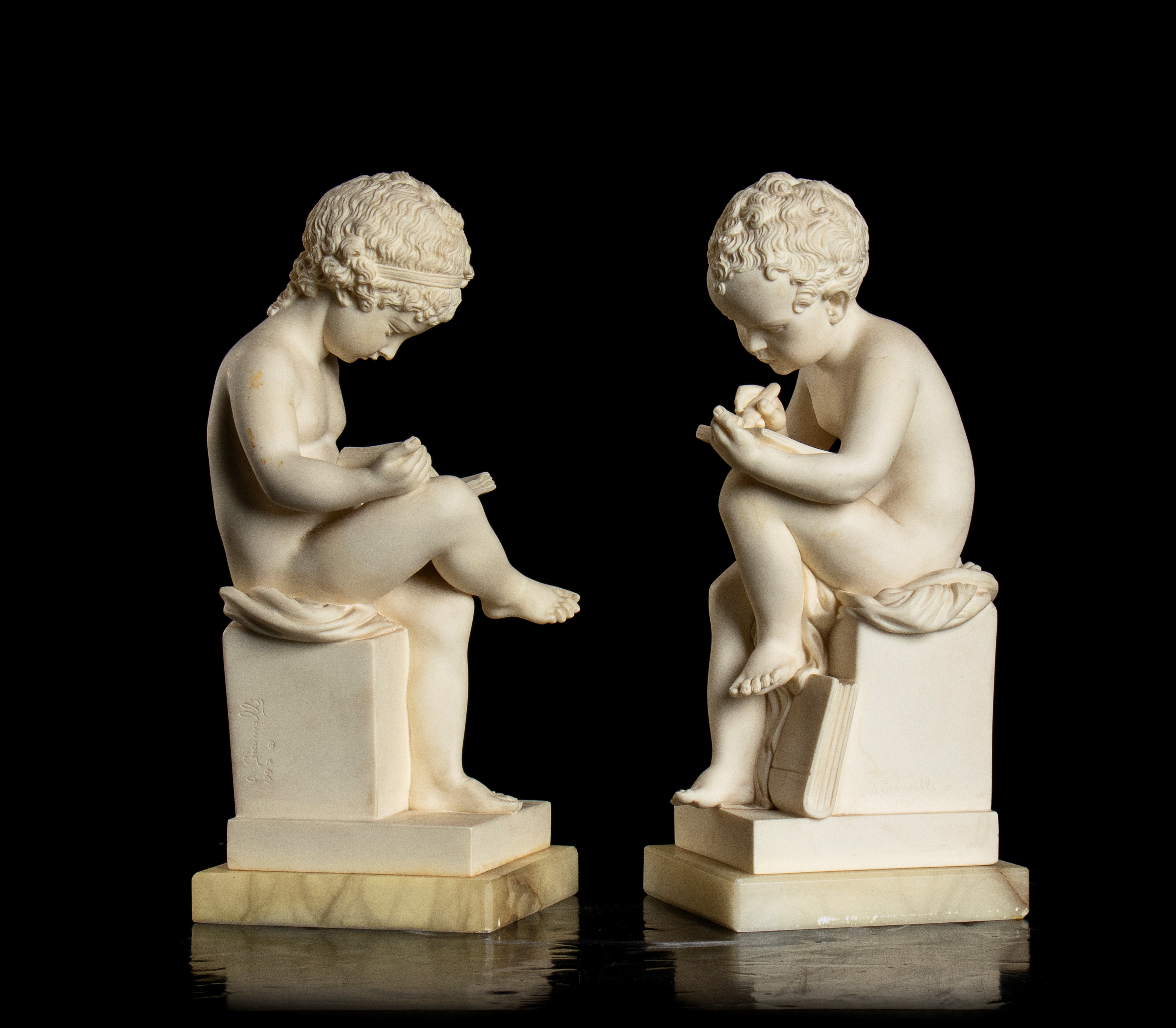 Coppia di piccole sculture in resina raffiguranti un putto che legge e un putto che scrive