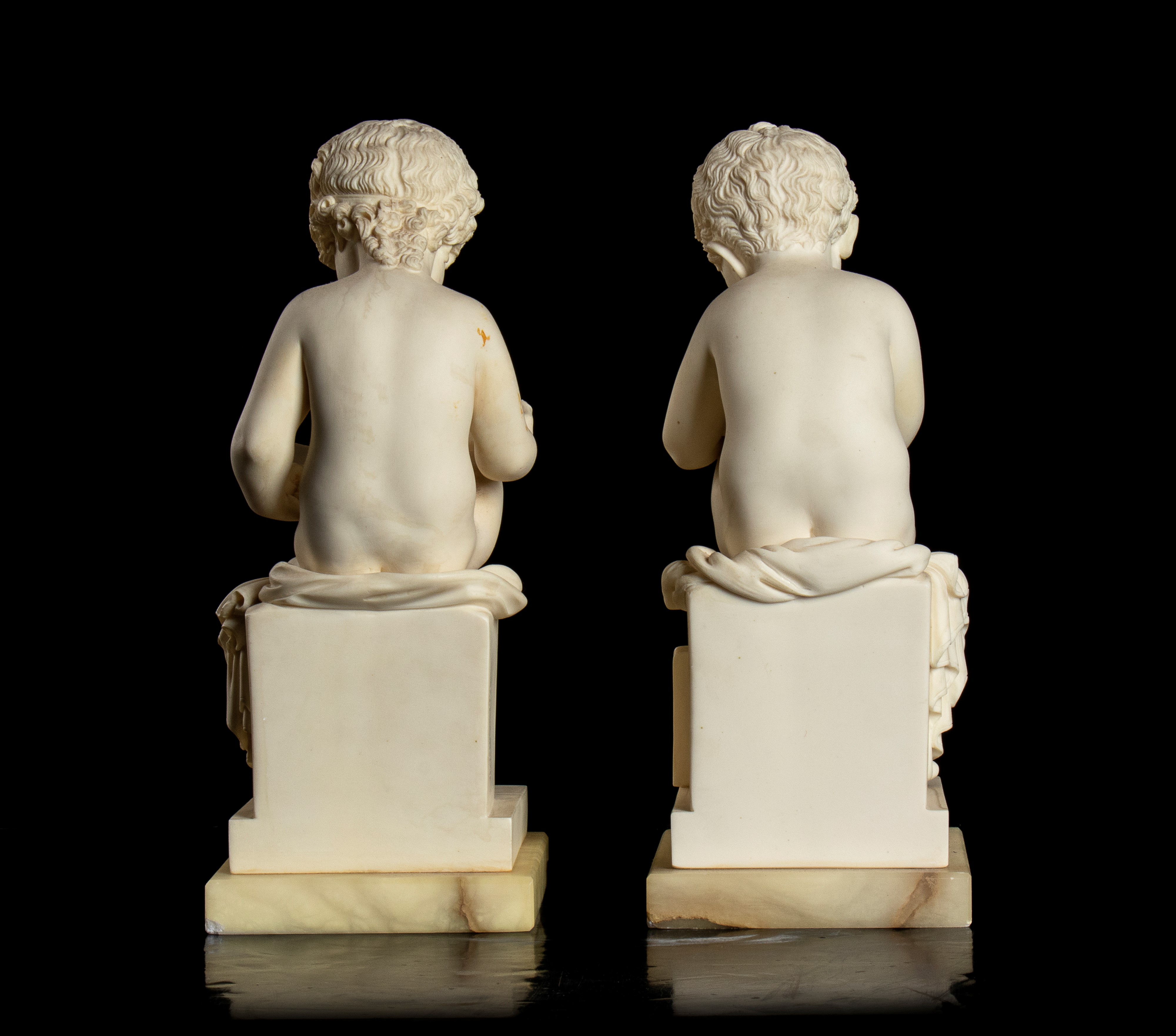 Coppia di piccole sculture in resina raffiguranti un putto che legge e un putto che scrive