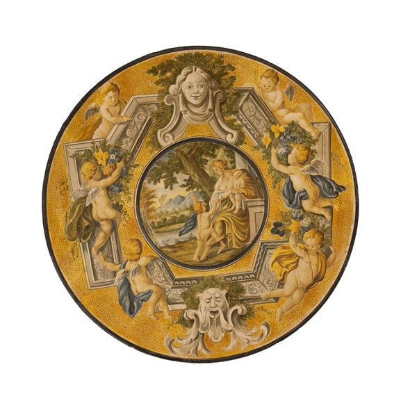 Grande piatto di ceramica lumeggiato in argento con al cavetto rappresentata l'Allegoria della Carità
