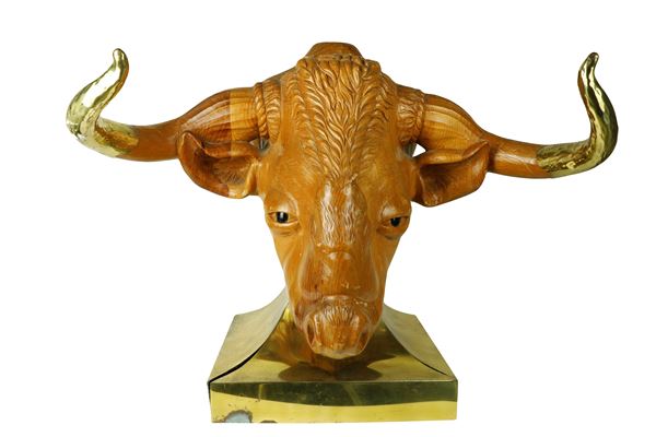 Testa di toro in legno scolpito con base in metallo dorato e corna rivestite da lamina di metallo dorato e sbalzato.