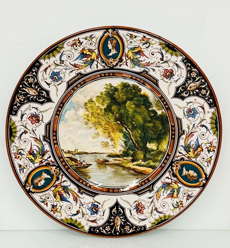 Piatto in ceramica con paesaggio fluviale nel cavetto e grottesche alla tesa