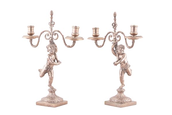 Coppia di candelieri in argento a due fuochi a forma di putti , XX secolo.