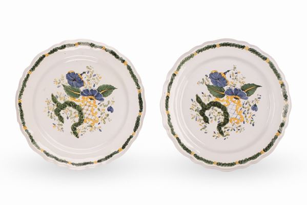 Coppia di piatti decorati a motivi floreali ed elementi rocaille nei toni del verde, blu e giallo.