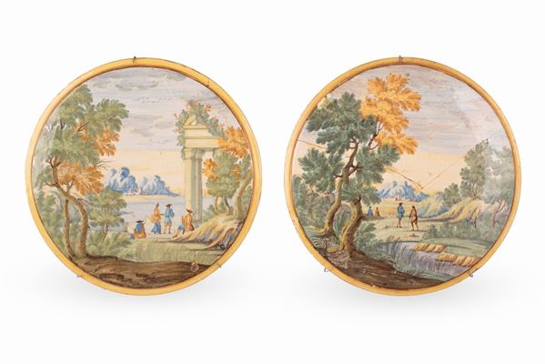 Manifattura castellana del XVIII secolo - Coppia di tondi in maiolica decorata in policromia con paesaggi e rovine animati da personaggi. Filettatura in giallo sul bordo.