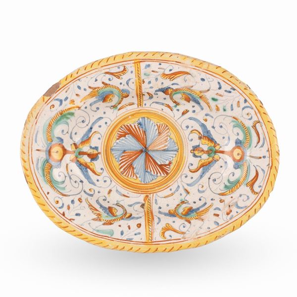 Manifattura di Deruta del XVII secolo - Vassoio ovale in maiolica decorato in policromia con motivi floreali e grottesche. Al centro motivo floreale nei tonni del rosso e del blu.