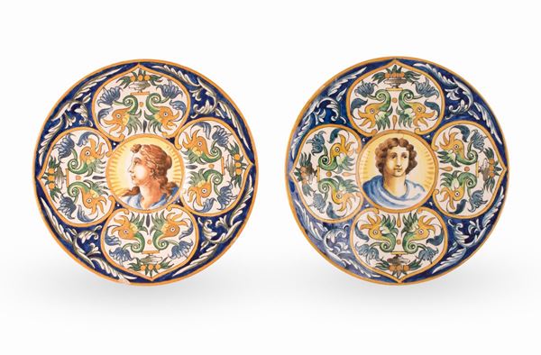 Manifattura di Pesaro del XIX secolo - Coppia di piatti in maiolica decorati in policromia. Nel cavetto figura maschile e femminile su fondo blu con motivo rocaille e bordi filettati in giallo