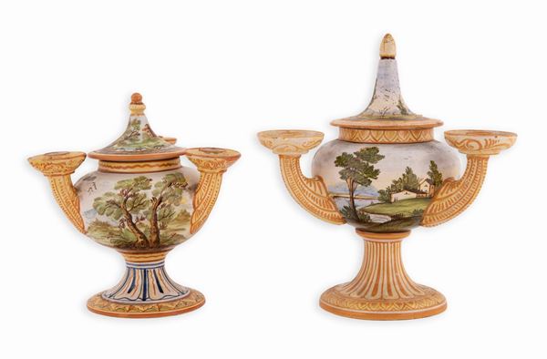 Manifattura castellana della prima met&#224; del XX secolo - Coppia di candelieri in maiolica decorati con paesaggi e case. Corpo globulare su alto piede da cui si dipartono tre bracci. Coperchio con presa fusiforme.