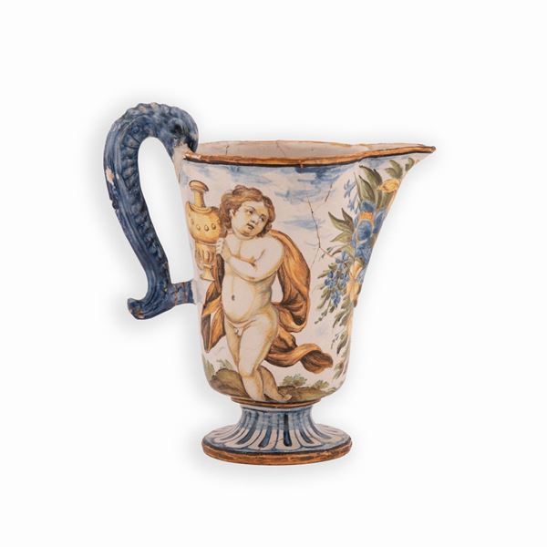 Manifattura castellana del XVII secolo - Versatoio in maiolica decorato in policromia con vaso baccellato e fiori sul fronte. Ai lati personaggi mitologici. Presa zoomorfa in blu cobalto.