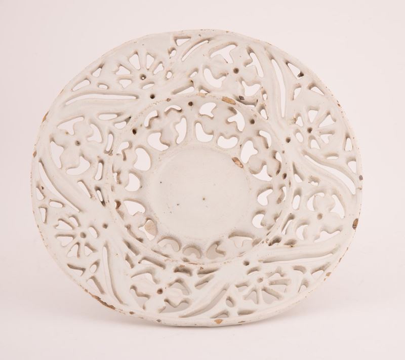 Crespina in maiolica a fondo bianco e traforata a formare motivo geometrico.