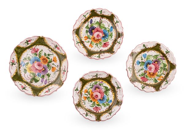 Lotto di centrotavola e 3 piatti in maiolica a bordo mistilineo, decorati in policromia con motivi vegetali e fiori