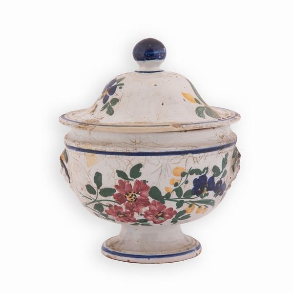Manifattura castellana del XIX secolo - Zuppiera in maiolica decorata in policromia con motivi floreali e bordature in blu. Ai lati mascheroni. Coperchio con presa sferica in blu. 