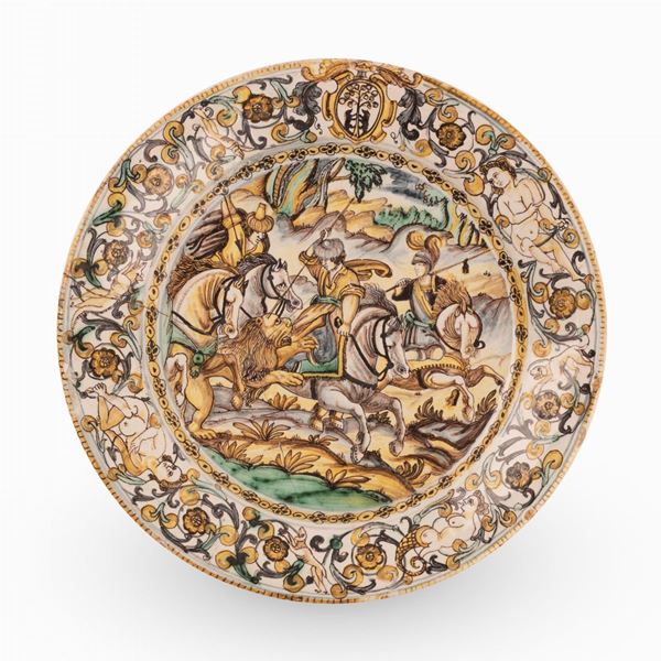 Francesco Angelo Grue - Piatto in maiolica decorato con girali fitomorfi, putti ed uno stemma sulla tesa e con scena di caccia al leone, nel cavo.