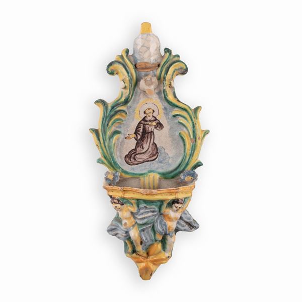 Manifattura di Cerreto Sannita attiva nel XVIII secolo - Acquasantiera in maiolica con decorazioni a rilievo e l'effigie di un Santo Francescano.
