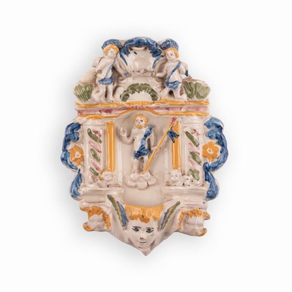 Manifattura castellana della seconda met&#224; del XVIII secolo - Acquasantiera in maiolica con decorazioni a rilievo recante al centro l'effigie di Cristo Risorto in atto benedicente.