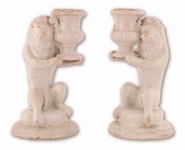 Manifattura dell'Italia meridionale del XIX secolo - Coppia di candelieri in maiolica bianca conformati in guisa di leone, stante a sorreggere un vaso.