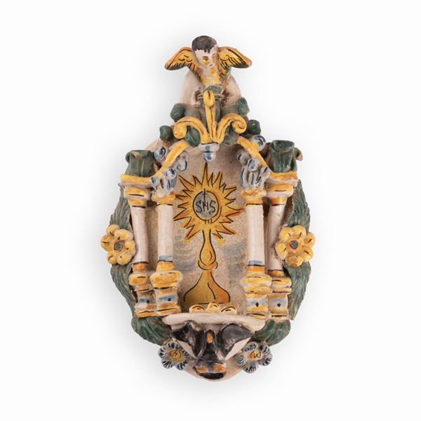 Manifattura di Cerreto Sannita attiva nel XVIII secolo - Acquasantiera in maiolica con decori a rilievo ed il simbolo eucaristico (IHS) nell'edicola centrale.