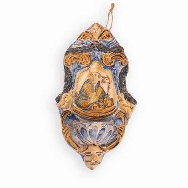 Manifattura castellana della seconda met&#224; del XVIII secolo - Acquasantiera in maiolica decorata con elementi a rilievo ed al centro, con l'effigie di un Santo Vescovo in atto benedicente (Sant'Emidio?)
