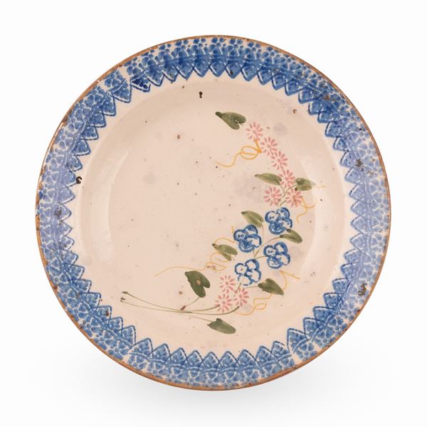 Manifattura abruzzese attiva tra il tardo XIX ed i primi del  XX secolo. - Grande piatto in maiolica decorato con motivi a stampo sul bordo e da un motivo fitomorfo stilizzato, nel cavo