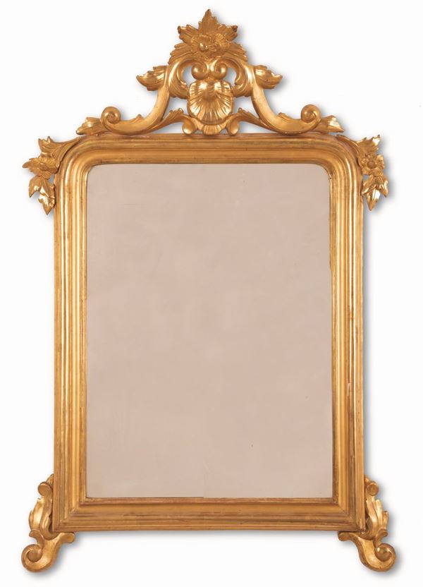 Manifattura romana - Specchio in legno intagliato e dorato con cimasa recante conchiglia e tralci di fiori. Piedi d'appoggio a riccio