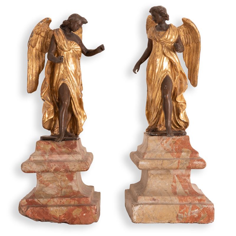 Coppia di sculture in metallo brunito e dorato raffiguranti angeli su antiche basi in marmo