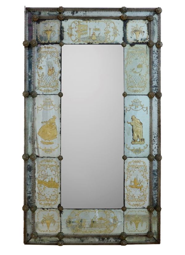 Antica specchiera di Murano decorata con elementi floreale a rilievo e scene veneziane incise e dorate. 