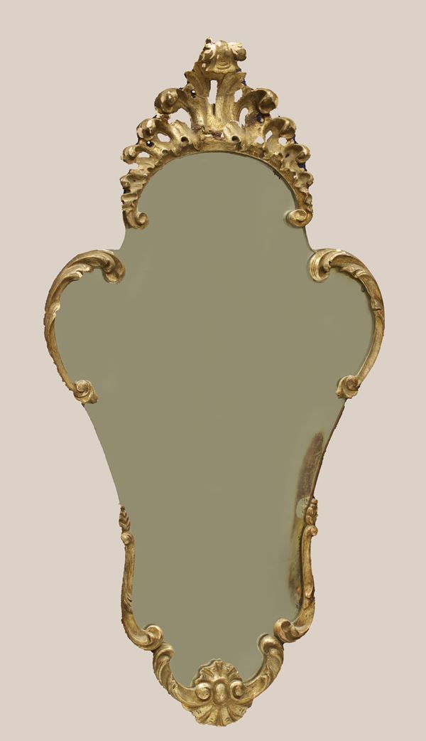 Specchiera veneziana della prima metà del XX secolo, composta da elementi in legno finemente sagomati, intagliati e dorati.