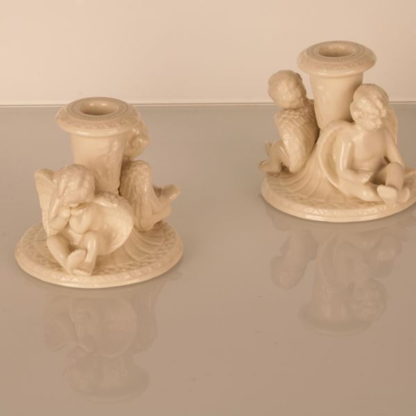 Coppia di bugie in bisquit riccamente decorate con putti alati che reggono con la schiena il porta candela.  - Asta Aperti per ferie:  l'asta di agosto. In occasione della 729esima Perdonanza Celestiniana - Gliubich Casa d'Aste