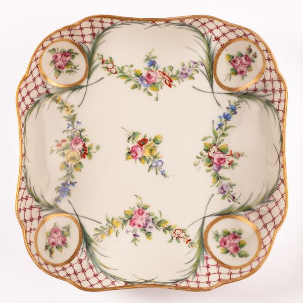 Piccolo vassoio quadrato in porcellana Sevres con decoro a treillage alternato da riserve con mazzetti floreali di rose unite da ghirlande. 