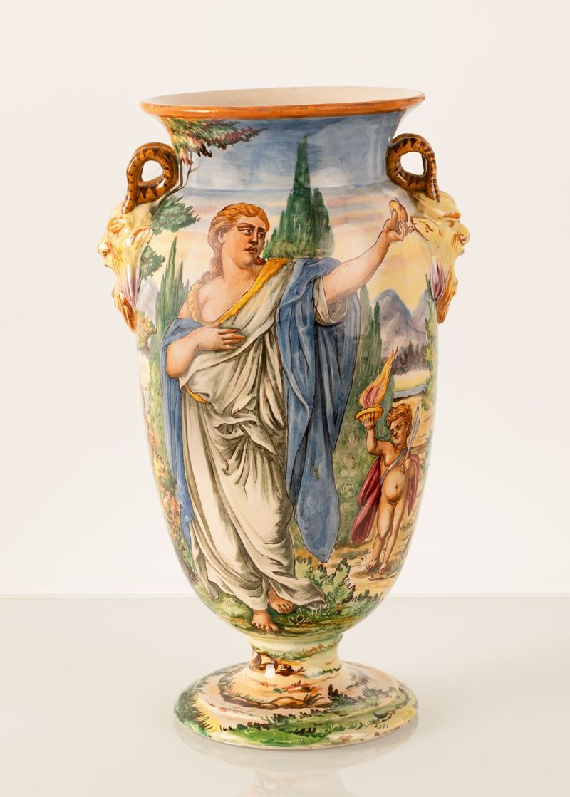 Vaso in maiolica a forma di urna con anse a rilievo imitanti due teste di fauni urlanti. Manifatt...