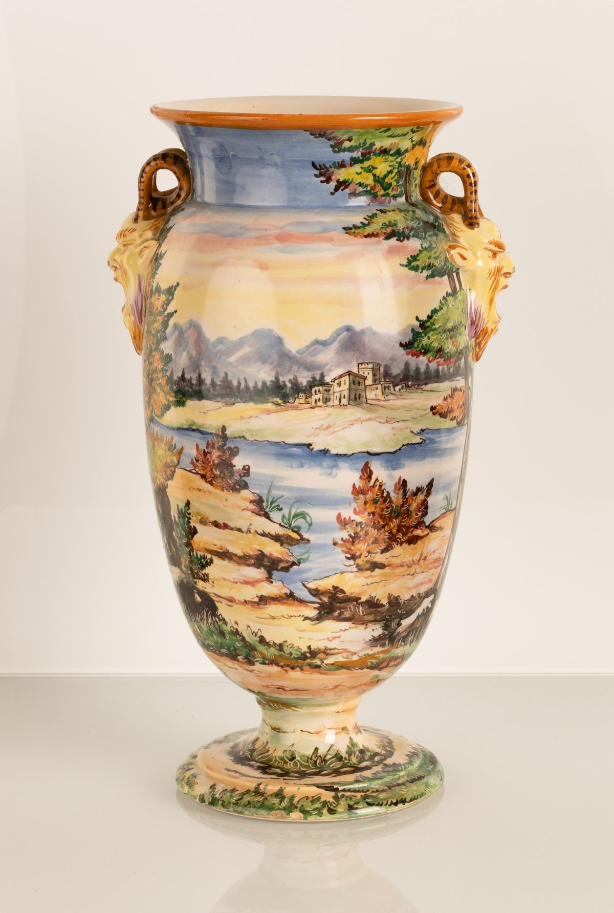 Vaso in maiolica a forma di urna con anse a rilievo imitanti due teste di fauni urlanti. Manifatt...