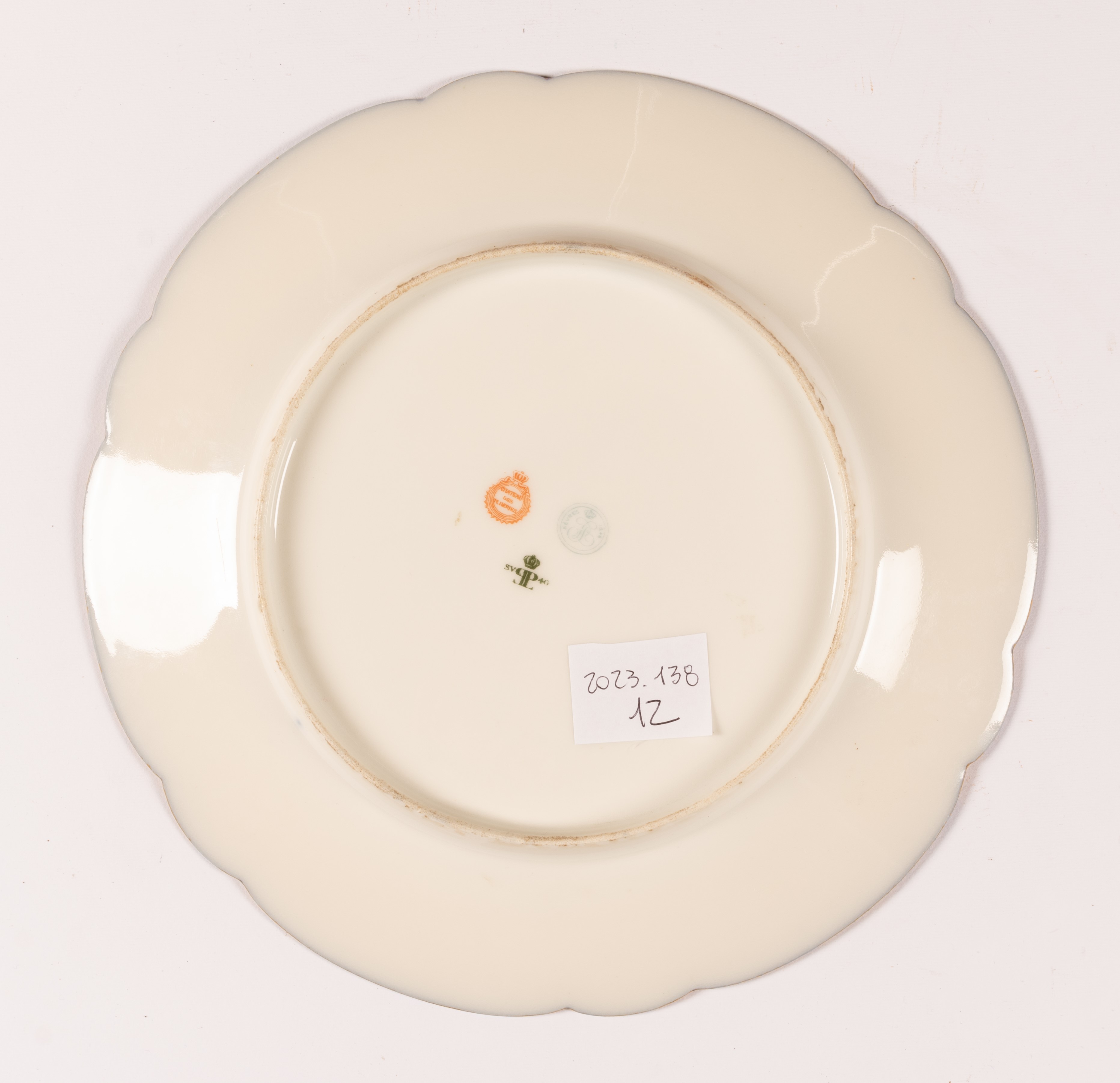 Piatto in porcellana Sevres con tesa a fondo blu e decoro in oro a volute e racemi.