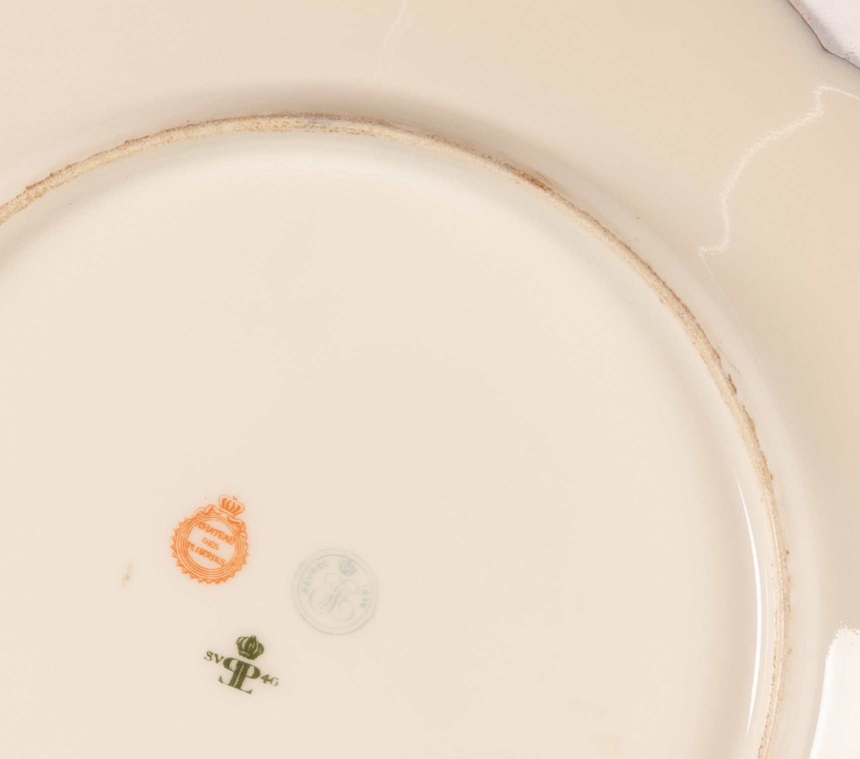Piatto in porcellana Sevres con tesa a fondo blu e decoro in oro a volute e racemi.