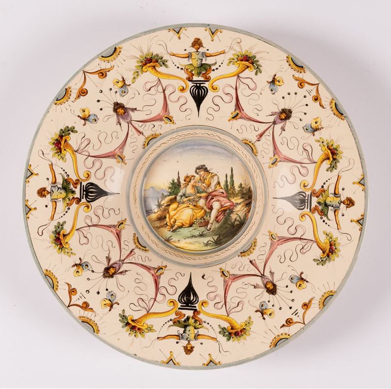 Grande piatto in maiolica con larga tesa decorata con motivi a raffaellesche di gusto neorinascim...