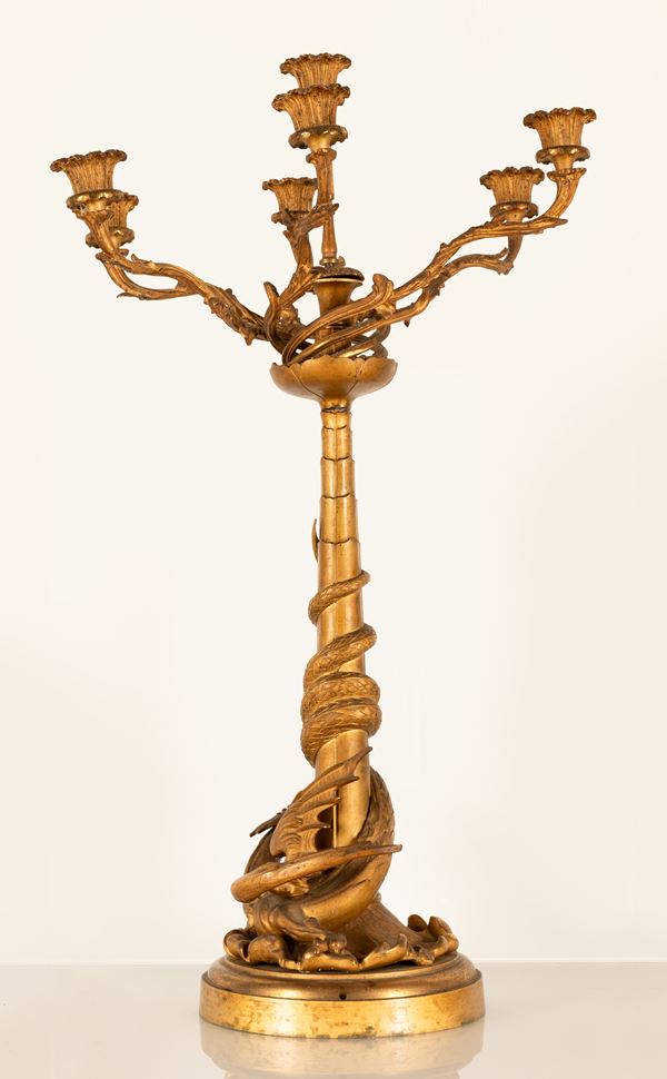 Grande candelabro a 7 fuochi in bronzo dorato. Figura di drago alato alla base con coda attorcigliata al fusto.