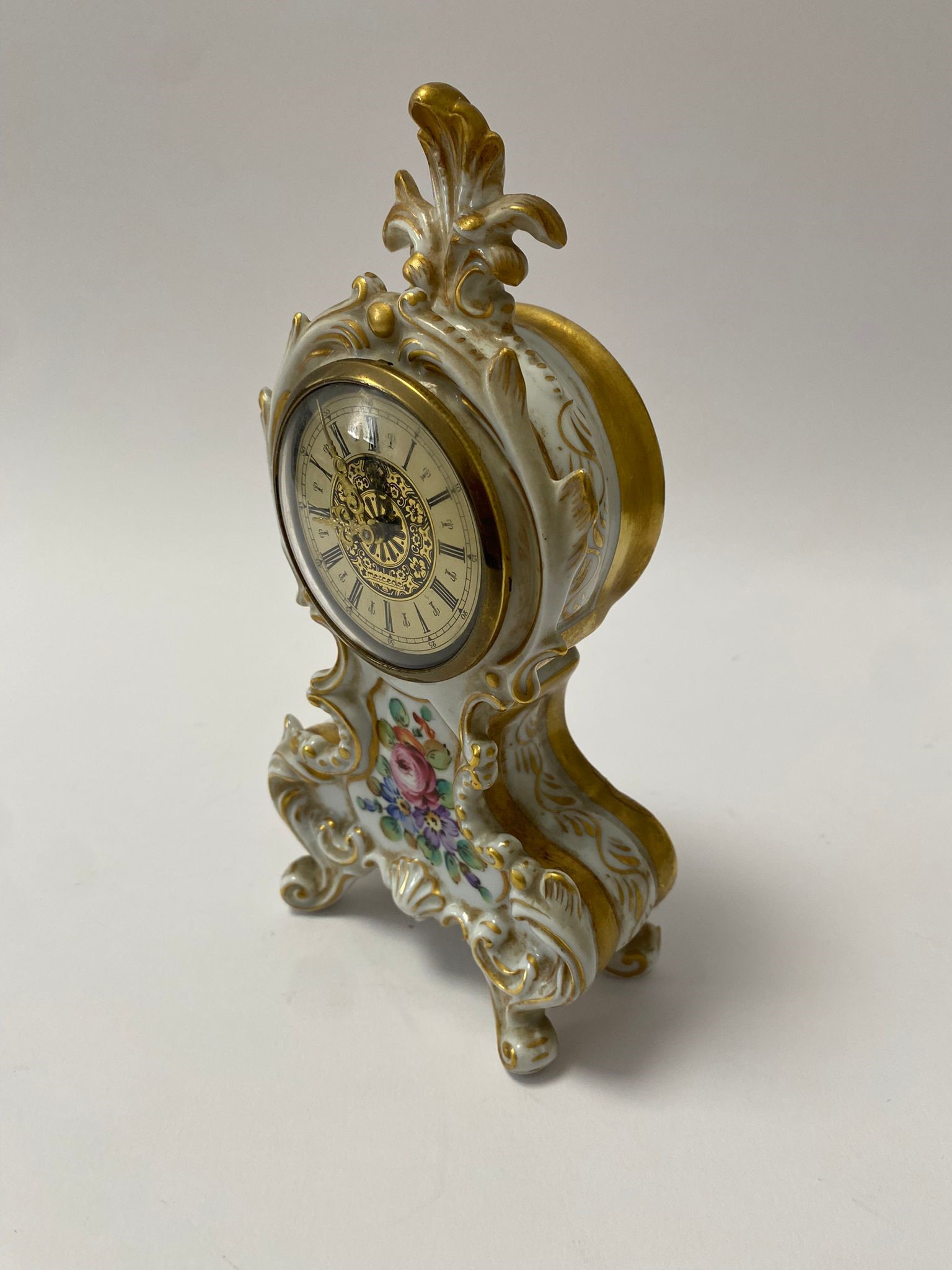 Piccolo orologio da camino in porcellana di Capodimonte con ricche volute e decori floreali