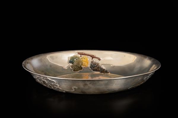 Centrotavola in argento 800/000 con decoro a rilievo policromo con tralci, pampini e uva ai bordi interni della tesa.