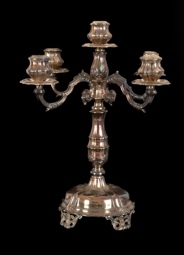 Elegante candeliere a cinque fiamme in argento  finemente lavorato con base a forma ellittica poggiante su quattro piedini traforati. Punzone 39PA