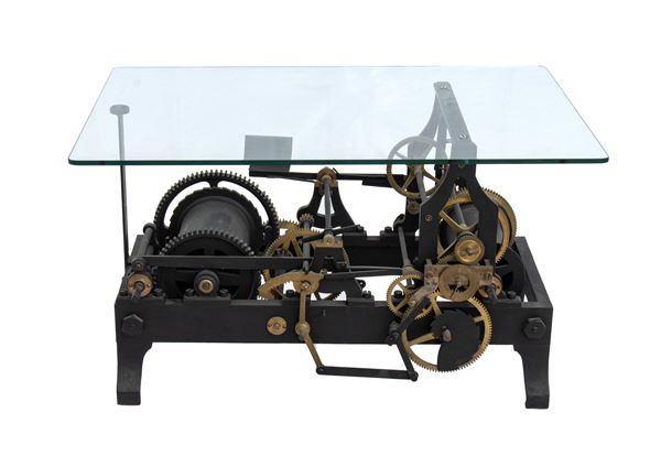 Industrial inspired table with glass top and base formed by large clock mechanism